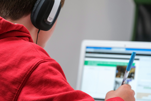 Student wearing headphones working on a laptop lesson