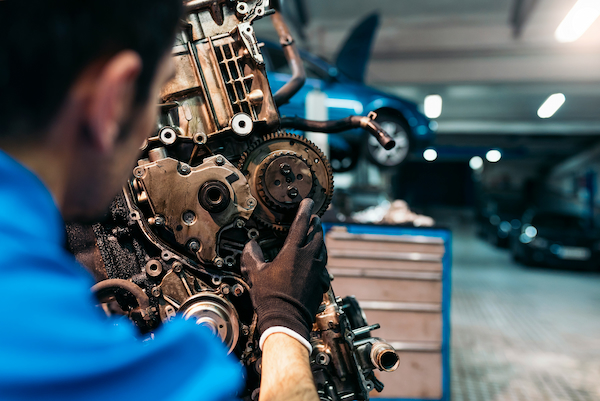 Technician inspecting an engine timing assembly in a repair shop